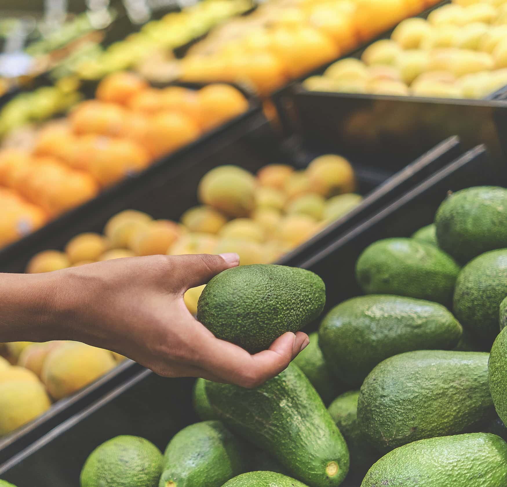Young Woman Choosing Avocados in Grocery Store. Concept of healthy food, bio, vegetarian, diet. Selective focus.